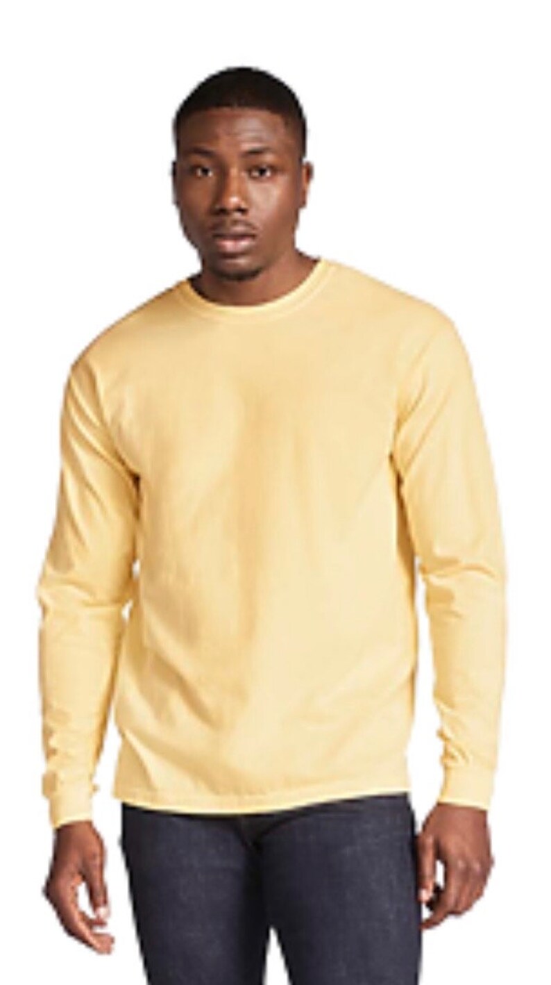 May include: A long-sleeved t-shirt in a pale yellow color. The shirt has a crew neck and a relaxed fit.