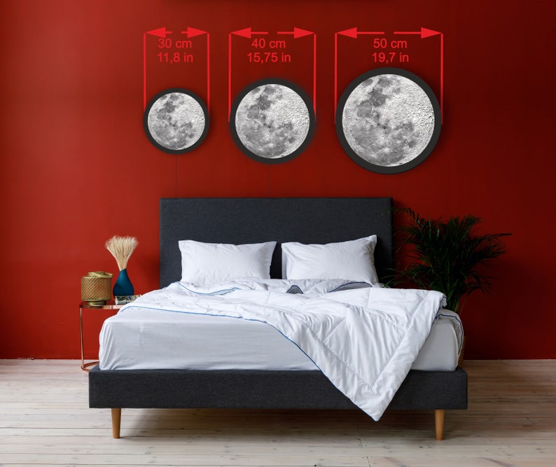 May include: Three round moon-shaped LED lights in different sizes, 11.8 inches, 15.75 inches, and 19.7 inches, hanging on a red wall above a gray bed with white bedding.