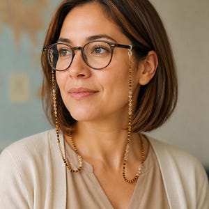 May include: A pair of brown-rimmed spectacles featuring a decorative beaded chain. The chain consists of alternating small brown tiger eye beads and clear faceted crystal beads, attached to the frames with clear silicone loops on each side.