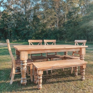 May include: A rustic wooden table and bench set with four chairs. The table and bench have a distressed white finish and turned legs. The chairs have a similar finish and a slatted back.