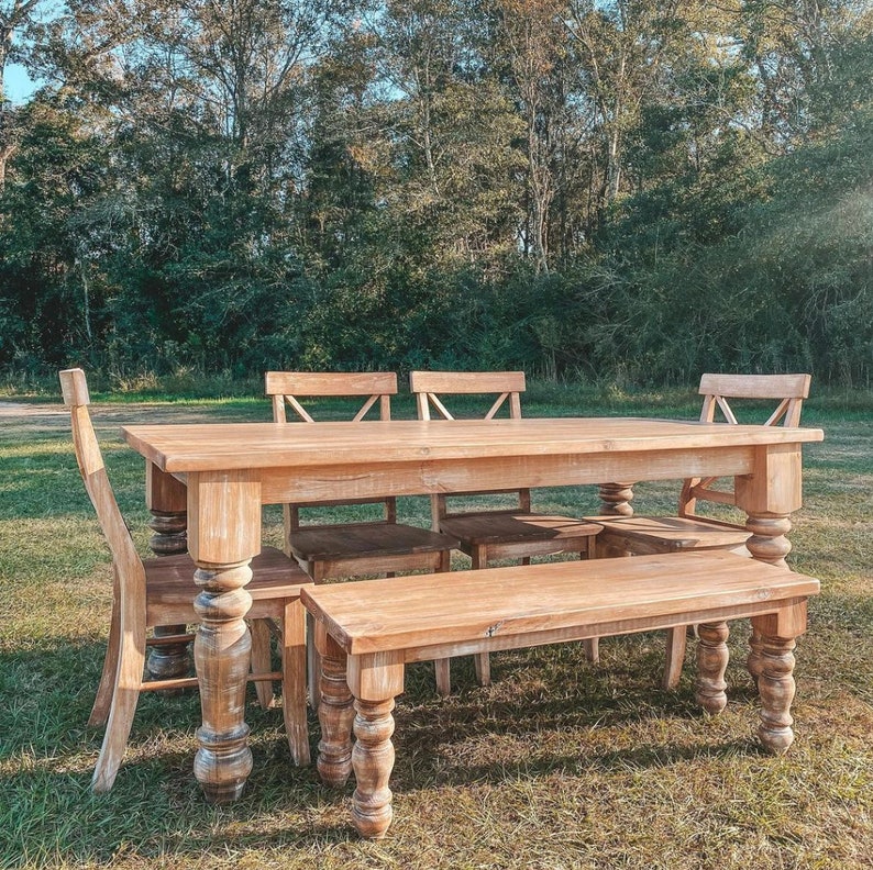 May include: A rustic wooden table and bench set with four chairs. The table and bench have a distressed white finish and turned legs. The chairs have a similar finish and a slatted back.