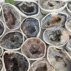 May include: A collection of agate geode slices with a variety of colors and patterns. The geode slices are polished and have a smooth, white surface. The interior of the geode slices is filled with crystals.