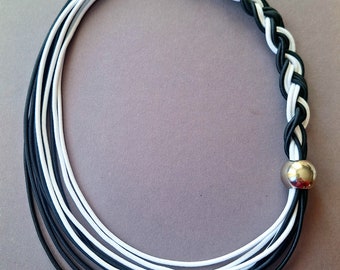 Op de afbeelding: Zwart-witte gevlochten ketting met een zilveren sluiting en een zilveren kraal aan het einde.