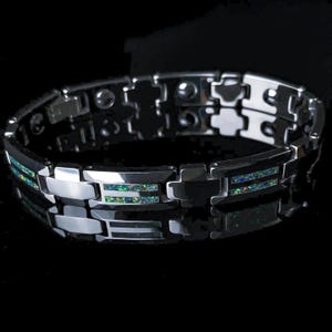 May include: A silver-toned bracelet with a link design. The bracelet features rectangular inlays with a green and blue iridescent pattern. The links are connected with a series of hinges. The bracelet is displayed on a black surface.