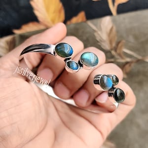 May include: Silver cuff bracelet with five iridescent labradorite gemstones. The stones are set in a curved silver band.