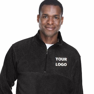 Könnte beinhalten: Weißer Keramikbecher mit schwarzem Henkel und dem Text "But First, Coffee" in schwarzer Schrift. Der Becher steht vor einem verschwommenen Hintergrund, der eine gemütliche Atmosphäre andeutet.