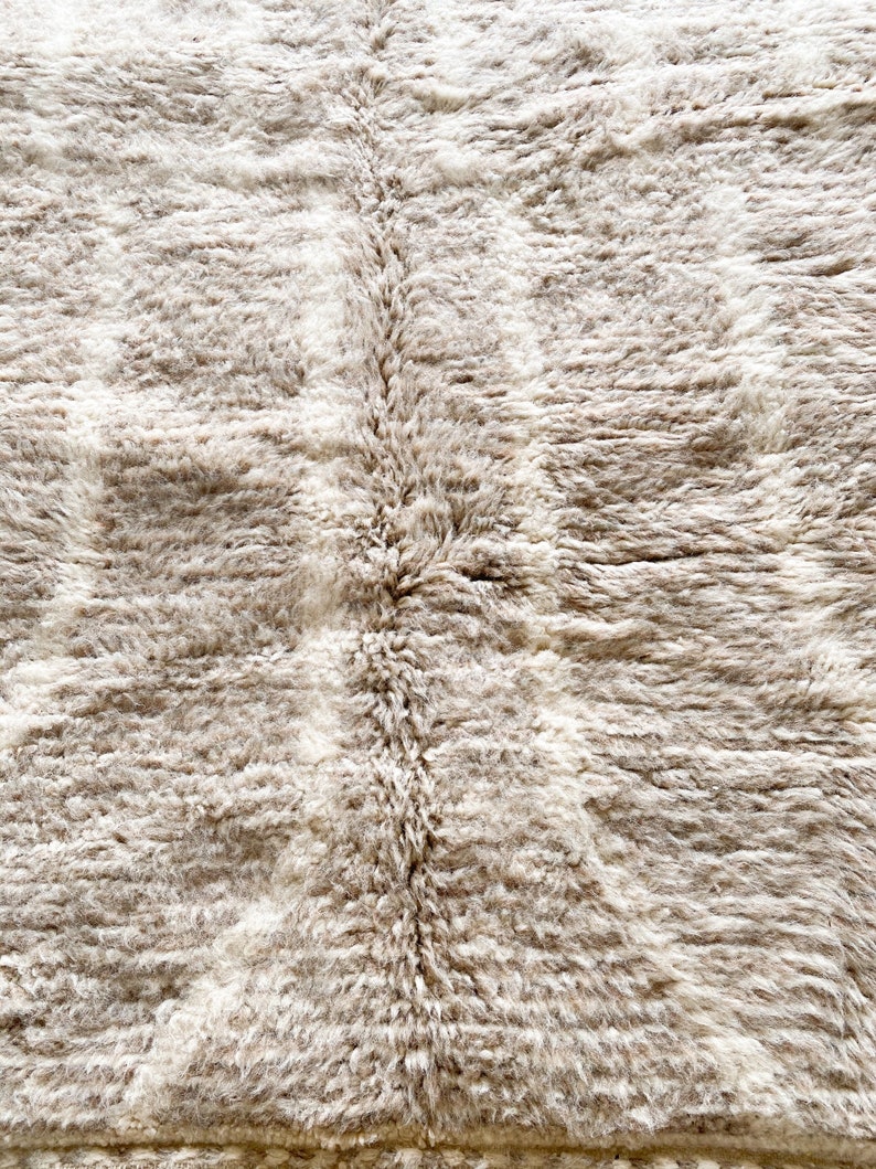Pu&ograve; includere: Primo piano di un tappeto beige e soffice con una texture sottile. Il tappeto &egrave; morbido, soffice e realizzato con un materiale di alta qualit&agrave;.