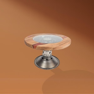 Puede incluir: Una pequeña mesa redonda con tapa de madera y un inserto de vidrio transparente. La tapa de madera está soportada por una base de metal. La mesa mide unos 30 cm de diámetro y 46 cm de altura.