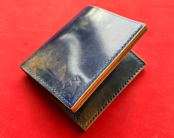 May include: A blue leather wallet with a distressed finish and a subtle embossed design. The wallet is folded in half and has a light brown interior.