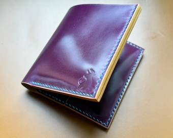May include: A purple leather wallet with a light blue stitching detail and a small logo on the front.