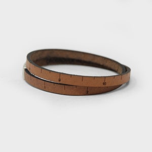May include: A brown leather bracelet with a ruler printed on it. The ruler goes from 1 to 10.
