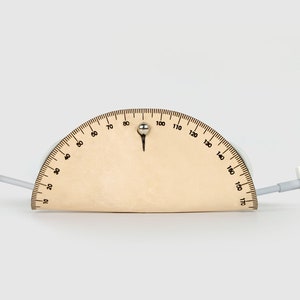 May include: A wooden protractor with a white cable running through it. The cable has a USB connector on one end and a lightning connector on the other end.