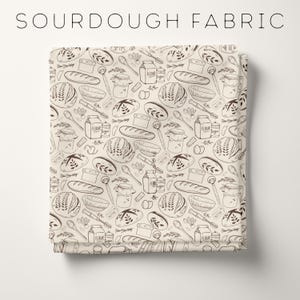 May include: Cream-colored fabric with a repeating pattern of bread, baking tools, and ingredients. The design includes loaves of bread, jars, spoons, and the words "Flour" and "Sugar". The text "SOURDOUGH FABRIC" is at the top.