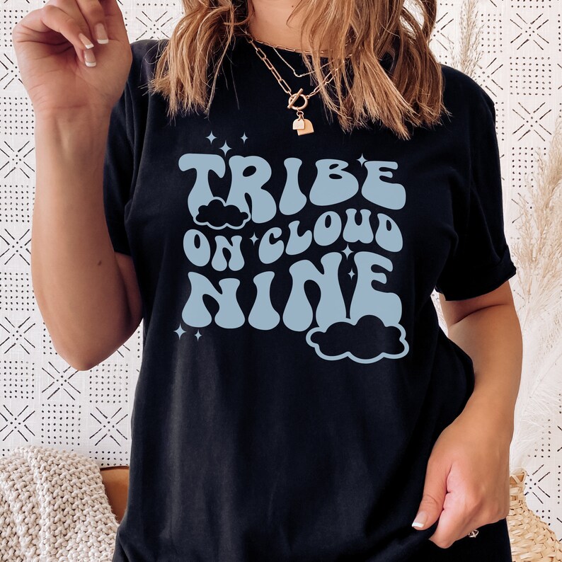 May include: Black t-shirt with a blue graphic that says "Tribe on Cloud Nine" in a retro font. The graphic includes clouds and stars.