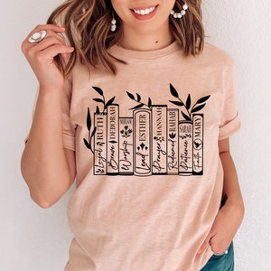 May include: A light pink t-shirt with a black graphic of a bookshelf with books that have names like "Loyal", "Brave", "Worship", "Lead", "Prayer", "Redeemed", "Patience", and "Faith".
