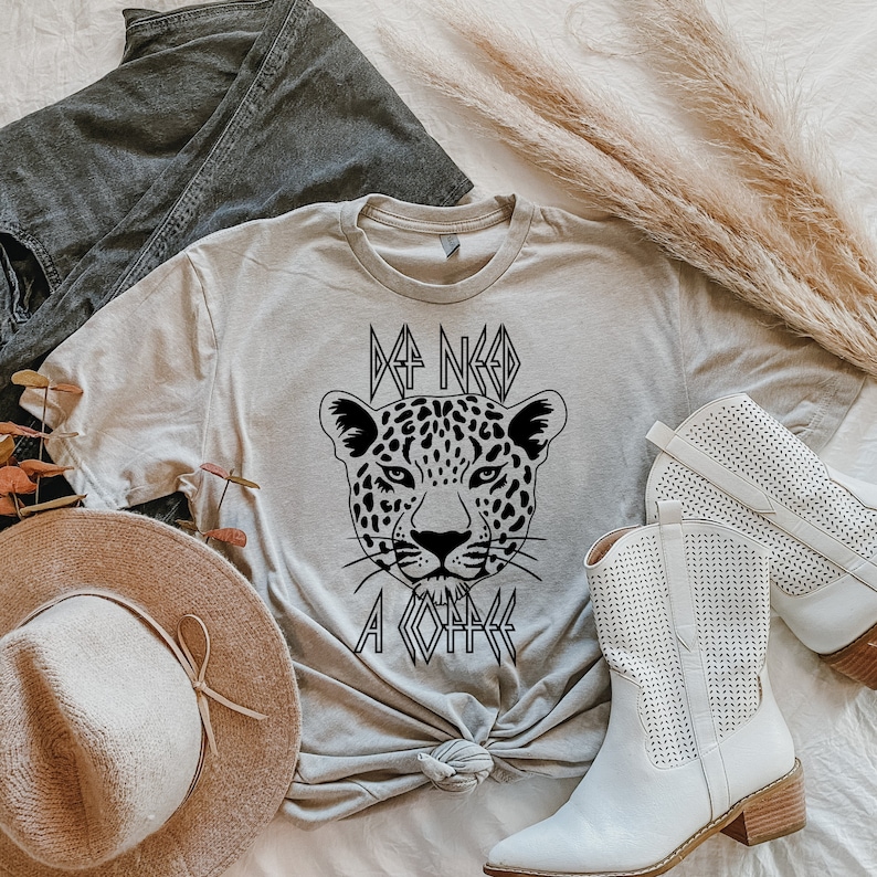 May include: A light gray t-shirt with a black graphic of a leopard's face and the text "I NEED A COFFEE".