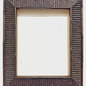 May include: Rectangular dark brown picture frame with a bamboo-style design. The frame has a textured surface and a light-colored interior, suitable for displaying artwork or photographs. The frame's corners are square.