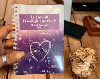 May include: A spiral-bound guidebook titled Le Guide de l'Améthyste Love Oracle, Mich'Aile Ange Tarot Tome 1, Toi & Moi. The cover features a purple gradient background with white bokeh lights, a hand-drawn heart, and the text Best-Seller.