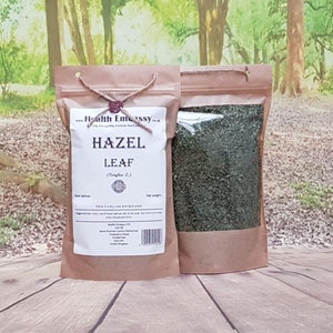 May include: A brown paper bag with a clear window showing dried green hazel leaves. The bag is labelled "Hazel Leaf (Corylus L.)" and includes the company name "Health Embassy".