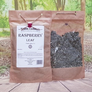 May include: A brown paper bag with a clear plastic window containing dried raspberry leaves. The bag is labelled "Raspberry Leaf (Rubus idaeus L.)" and includes information about the product, such as best before date, storage instructions, and suggested use.