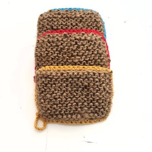 May include: A stack of four brown knitted dishcloths with colourful trim. The top dishcloth has a blue trim, the next has a red trim, the next has a yellow trim, and the bottom dishcloth has a yellow trim.