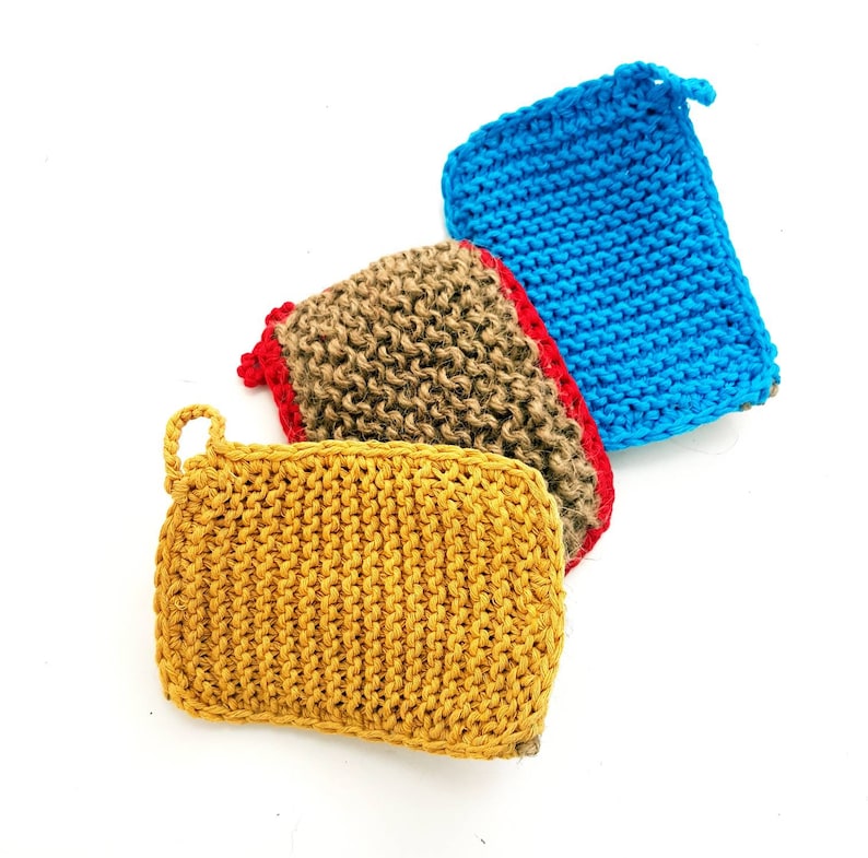 May include: Three knitted dishcloths in different colours: blue, brown, and yellow. The cloths are made of a textured yarn and have a slightly rough surface.