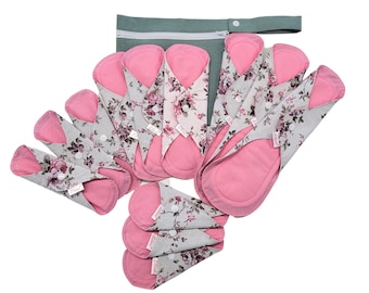 May include: A set of 10 reusable cloth menstrual pads with a floral print and pink lining. The pads are folded and arranged in a pile with a gray zippered pouch.