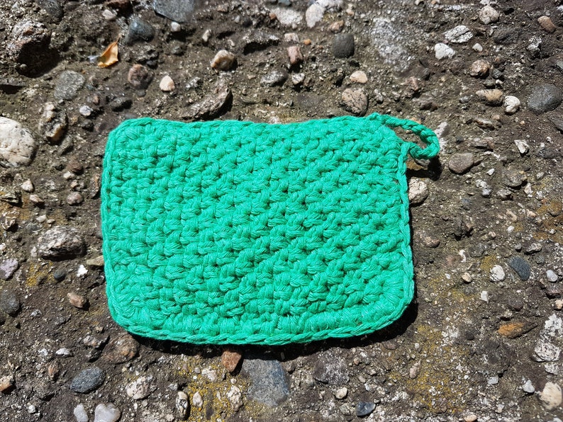 May include: A green crocheted dishcloth or pot holder with a loop for hanging.