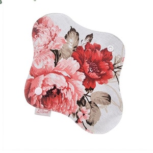 May include: A reusable cloth menstrual pad with a floral print featuring pink and red roses on a beige background. The pad has two white snaps on the sides and the text "Lilina" is printed in pink on the bottom left corner.