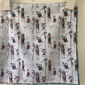 May include: A white fabric with a teal border features a repeating pattern of Jack Skellington and Sally from The Nightmare Before Christmas. The characters are depicted in various poses, including holding pumpkins and sweets.