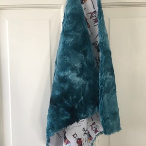 May include: Teal faux fur scarf with a white cotton lining featuring a repeating pattern of characters from The Nightmare Before Christmas.
