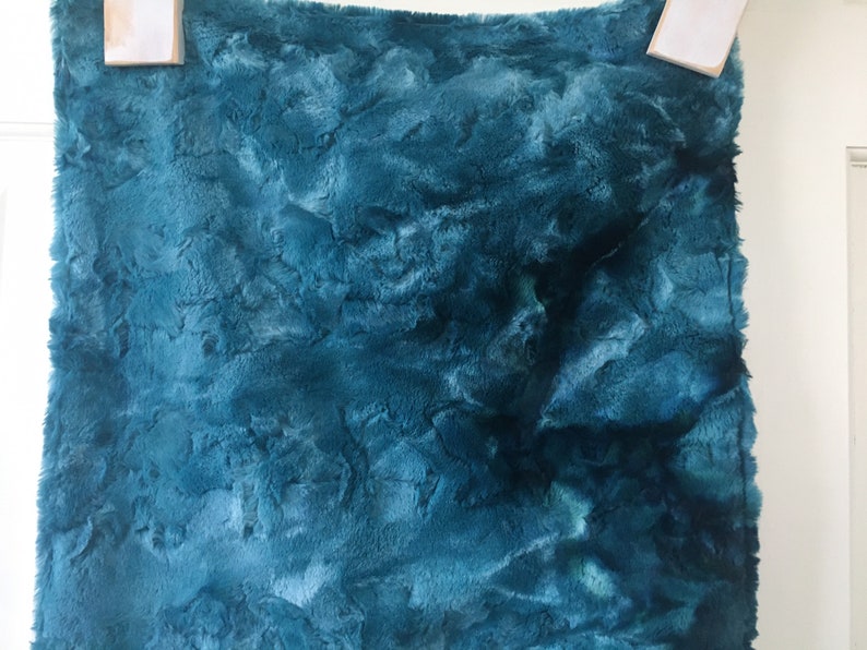 May include: Teal blue faux fur fabric with a soft, fluffy texture.