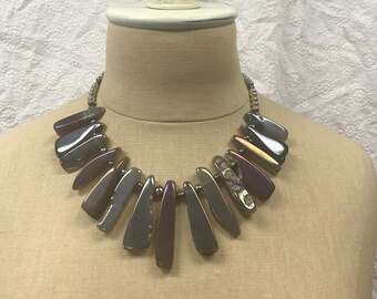 May include: A necklace with iridescent, gray, and purple agate stones in a graduated, fan-shaped design.