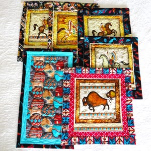 May include: A collection of Native American-themed wall hangings. The artwork features images of Native Americans on horseback, pottery, and a bison. The borders are adorned with colorful patterns and designs in red, turquoise, and black.