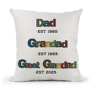 May include: A white cushion with the words "Dad -EST 1965-" "Grandad -EST 1993-" and "Great Grandad -EST 2023-" in tartan lettering.