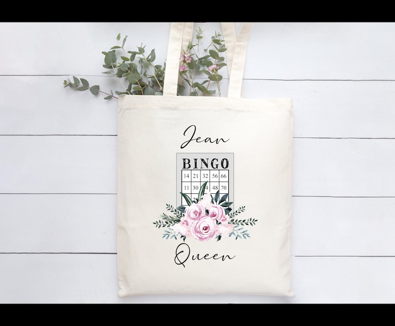 May include: A white tote bag with a floral design and the text "Jean Bingo Queen". The bingo card has numbers 14, 21, 32, 56, 66, 11, 30, 4, 48, 70.