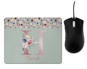 May include: A light green mouse pad with a floral border and a pink letter H in the center. The letter H is decorated with a watercolor floral bouquet. The name "Hannah" is written below the letter H.