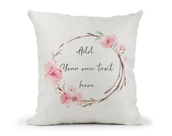 May include: A white pillow with a floral wreath design. The wreath is made of brown branches and pink flowers. The text "Add your own text here" is written in the center of the wreath.