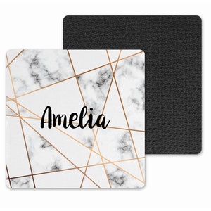 May include: White marble coaster with gold geometric lines and the name Amelia in black script.
