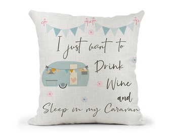 May include: A white pillow with a blue and white caravan illustration and the text "I just want to drink wine and sleep in my caravan". The caravan has a pink heart on the door and a string of bunting above it.