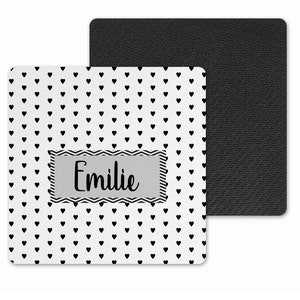 May include: White coaster with a black heart pattern and the name "Emilie" in a grey rectangle. The coaster has a black non-slip backing.