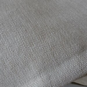 May include: Close-up of a light beige fabric with a woven texture.
