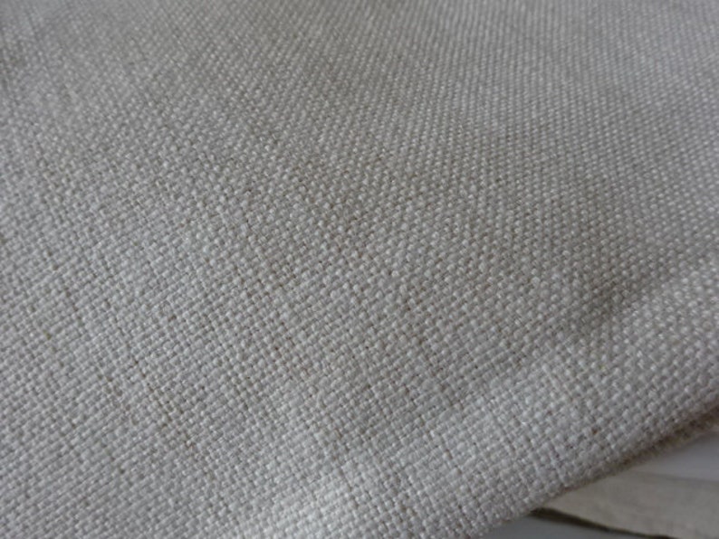 May include: Close-up of a light beige fabric with a woven texture.