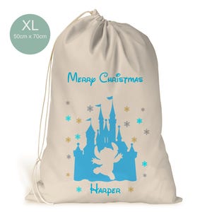 May include: A large, beige canvas sack with a drawstring closure. The sack is decorated with a blue silhouette of a castle and a blue Stitch character. The text "Merry Christmas" and "Harper" are printed on the sack. The sack is 50 cm x 70 cm.