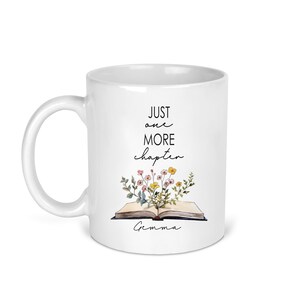 May include: White ceramic mug with black text that reads "Just one more chapter" and a floral illustration of an open book. The name "Gemma" is written below the book.