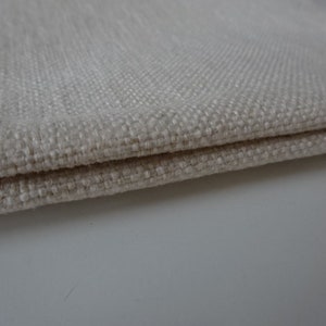 May include: Close-up of a folded piece of off-white fabric with a textured weave.