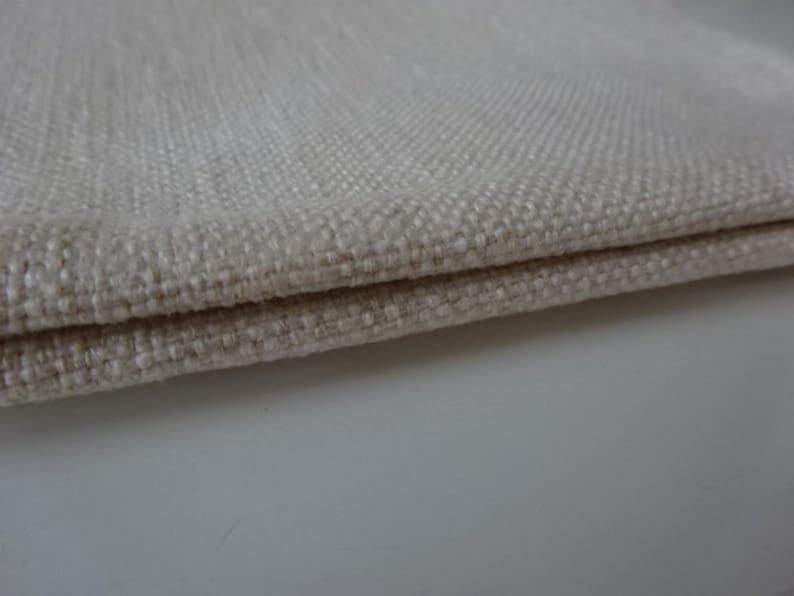 May include: Close-up of a folded piece of off-white fabric with a textured weave.