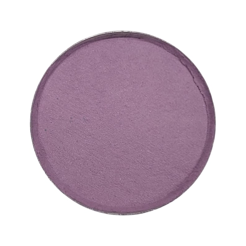 May include: A round, pressed eyeshadow pan in a muted purple color. The eyeshadow has a matte finish and is set in a silver metal compact. The product is isolated on a white background.