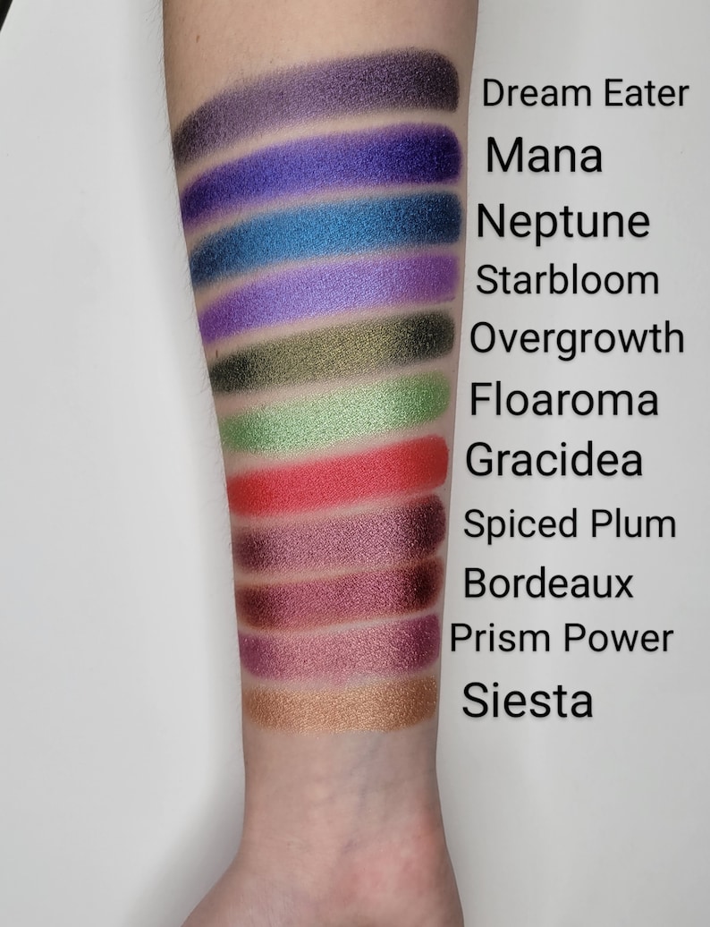 Puede incluir: Un primer plano de un brazo con 10 muestras de sombra de ojos. Las muestras est&aacute;n etiquetadas de arriba a abajo: Dream Eater, Mana, Neptune, Starbloom, Overgrowth, Floaroma, Gracidea, Spiced Plum, Bordeaux, Prism Power y Siesta.