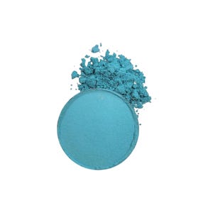 Puede incluir: Un compacto de sombra de ojos azul redondo con una pequeña cantidad de polvo derramado alrededor.